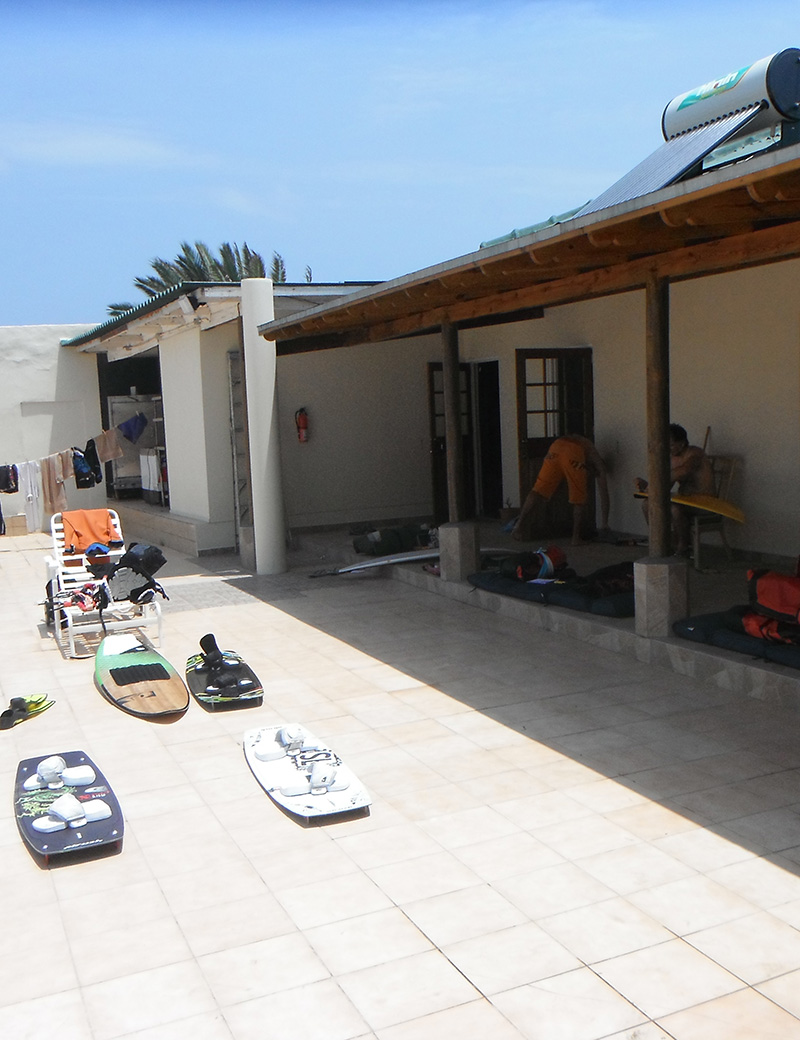 Kiteboards laid out in the Kite Inn courtyard with gear-washing area in the background